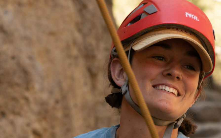 woman smiling while rock climbing on outward bound course